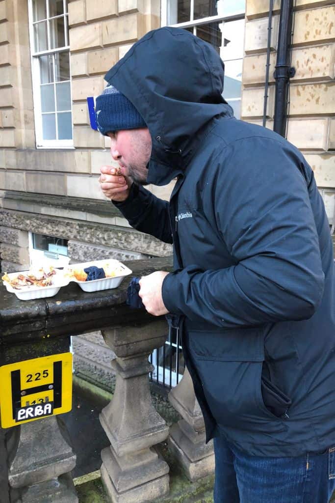 My husband eating our first run of Wings, Edinburgh outside on the Royal Mile.