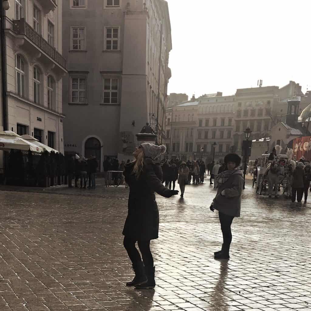 A 2 Day Krakow Itinerary Dancing through the streets of the Main Market Square during winter in Krakow on a rainy day.