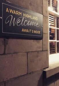 Sign outside a great pub in Edinburgh lit up by an overhead light at night