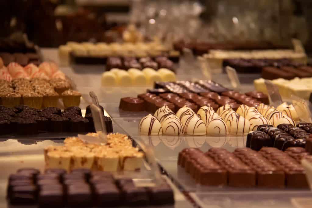 Is Bruges Worth Visiting Belgian chocolates in different shapes, lined up in a display. Chocolates in Belgium are simply divine.