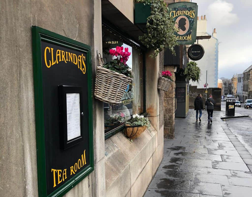 The exterior of Clarinda’s Tea Room, a charming establishment with a classic black and green sign, flower baskets, and a cozy ambiance, perfect for a cultural stop on a 1 week Scotland itinerary.