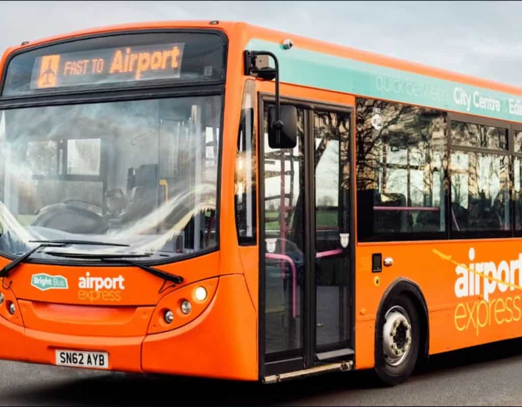 A bright orange "Airport Express" bus displaying "Fast to Airport" on its sign, offering a convenient travel option for visitors.