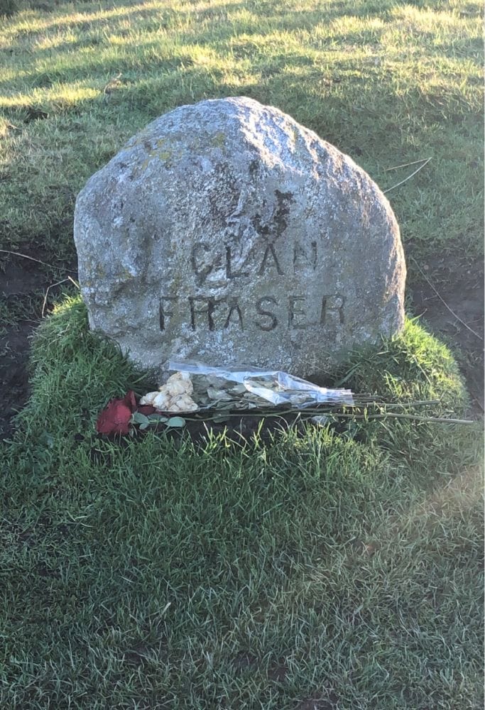 Memorial stone marked "Clan Fraser" with a small bouquet of white and red flowers laid at its base, located at Culloden Battlefield—featured in the Best Outlander Tours in Scotland.