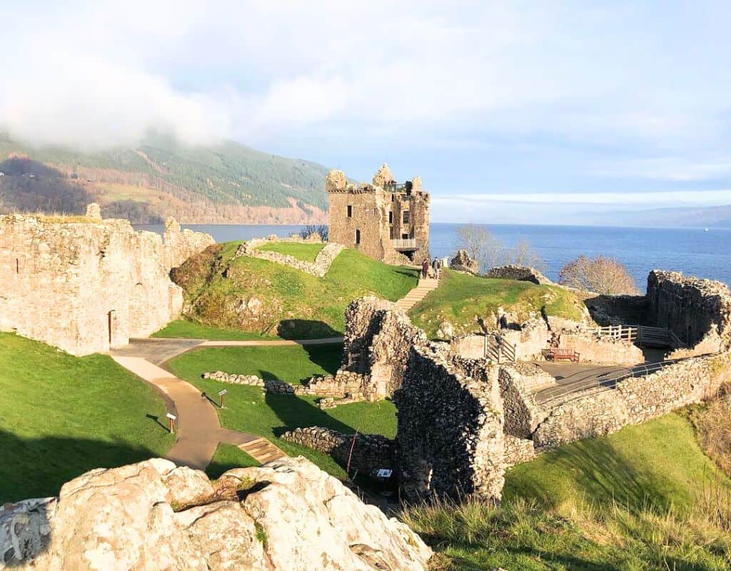 Sunlight illuminates the ruins of Urquhart Castle perched above Loch Ness, with its crumbling walls and lush green grounds drawing visitors year-round. For anyone asking โIs Loch Ness worth visiting?โโthis breathtaking view offers a resounding yes.
