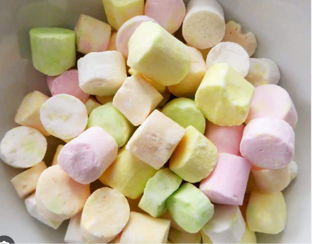 A bowl filled with colorful Scottish tablet candy in soft pastel shades of yellow, green, pink, and white—sweet, crumbly treats often found in local shops.