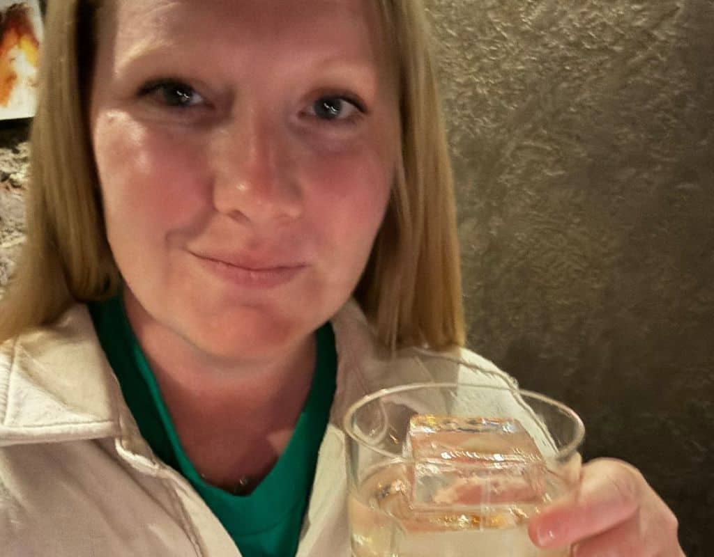 Taylor holding a cocktail with a large ice cube while enjoying an evening out in Prague, part of a memorable 3 Days in Prague itinerary.