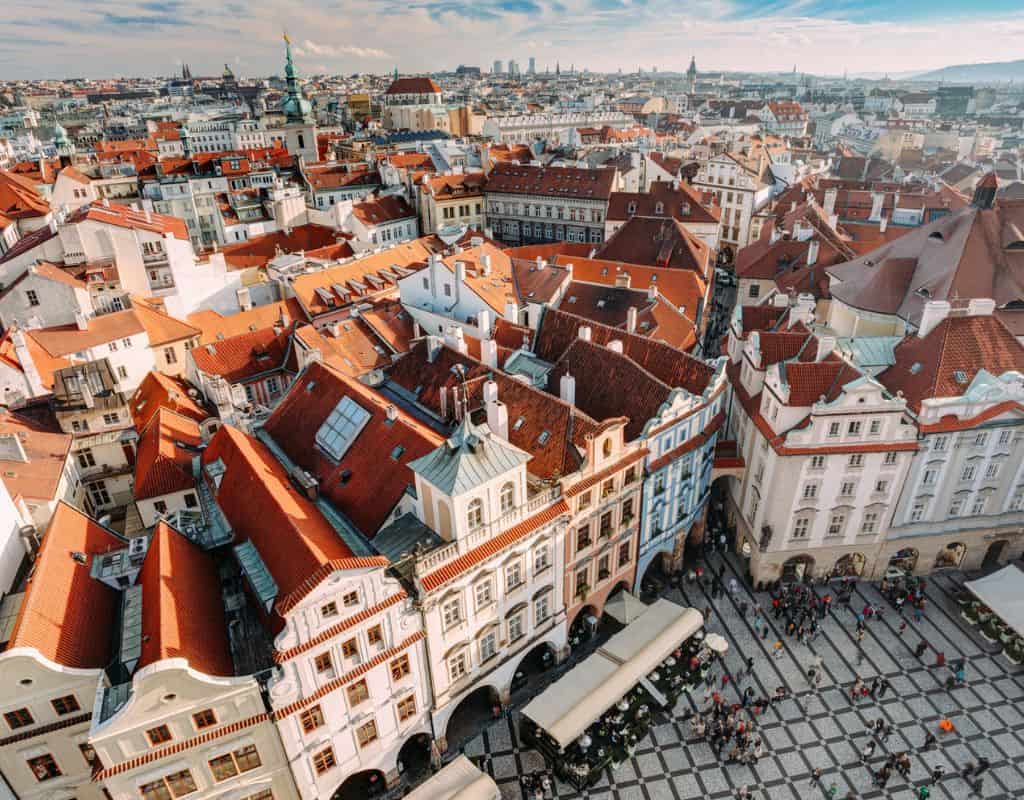 Panoramic aerial view of Prague’s Old Town showcasing red rooftops, historic architecture, and bustling streets filled with visitors.