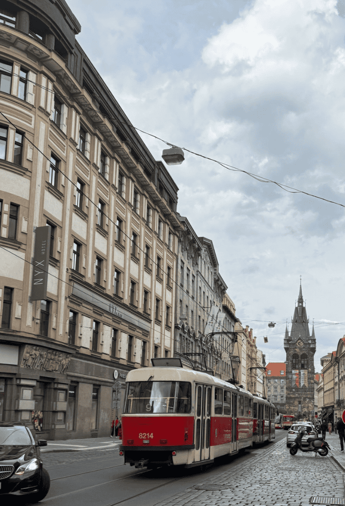 Red Prague tram traveling along a cobblestone street lined with historic buildings and city architecture during 3 Days in Prague.