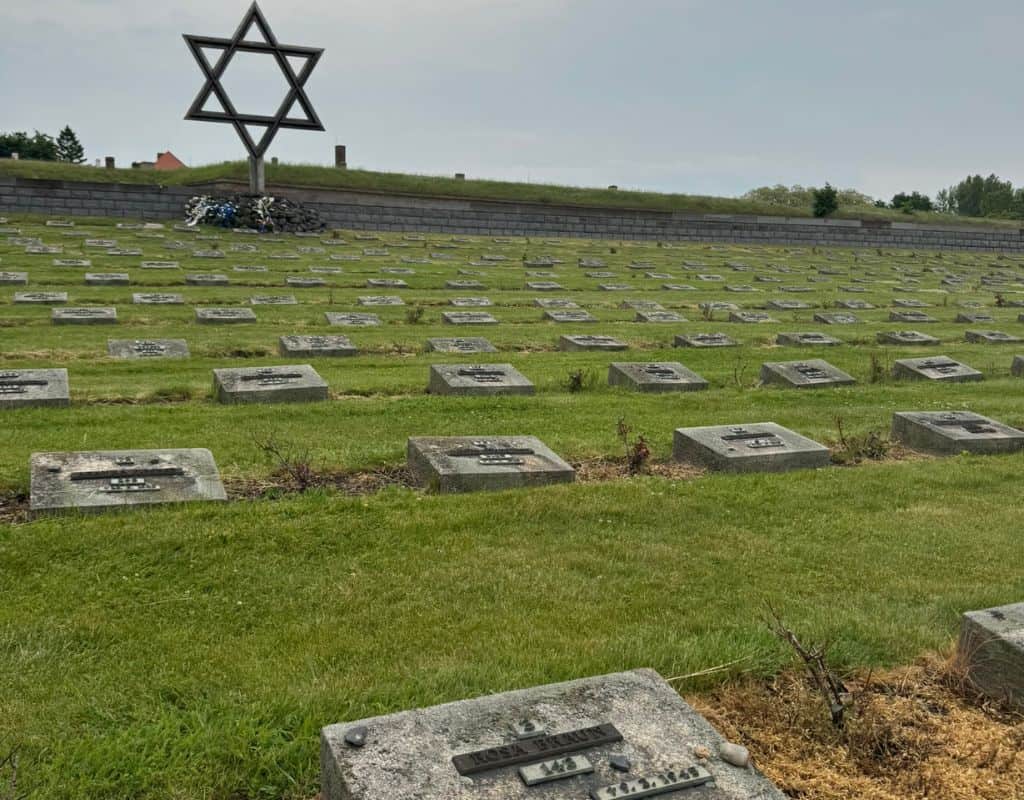 Rows of memorial plaques beneath a large Star of David monument at the former Theresienstadt concentration camp memorial site near Prague, honoring Holocaust victims during 3 Days in Prague.